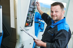 industrial worker operating cnc turning machine in metal machining industry